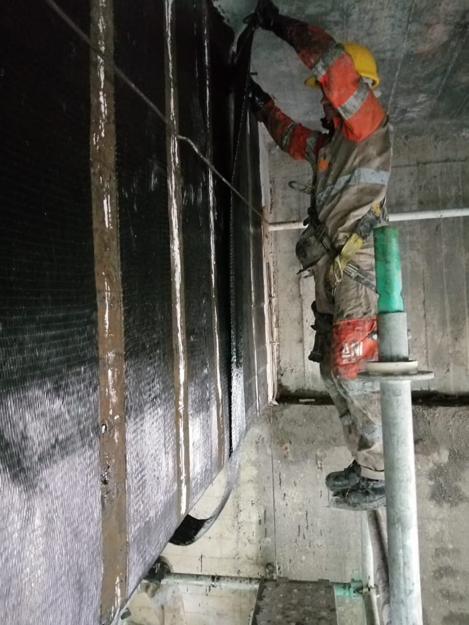 Operario instalando tejido en fibra de carbono como refuerzo a cortante en una viga